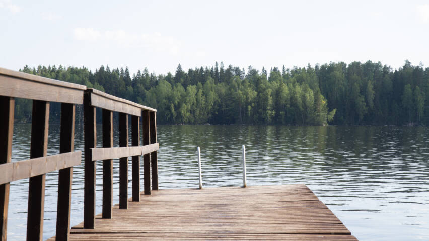 Laituri ja sen päässä järveen laskevat uimatikkaat.