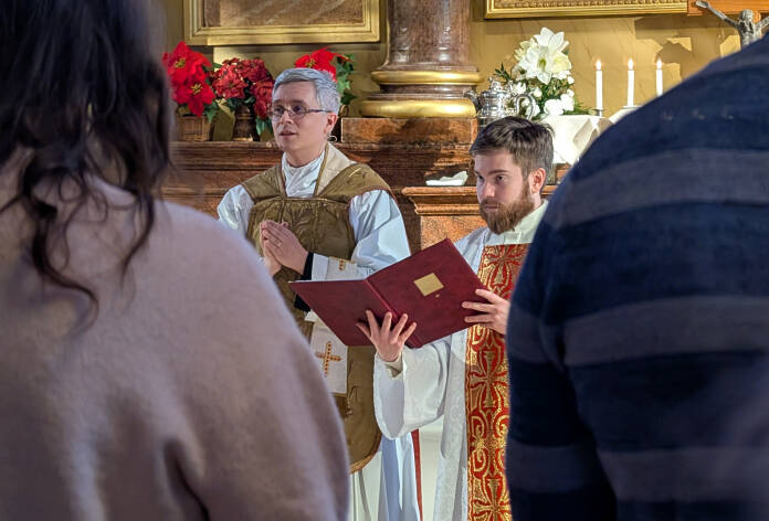 Liturgi kirkon kuorissa kultaisessa messukasukassaan ja alidiakoni vierellään valkoisessa tunikassa.